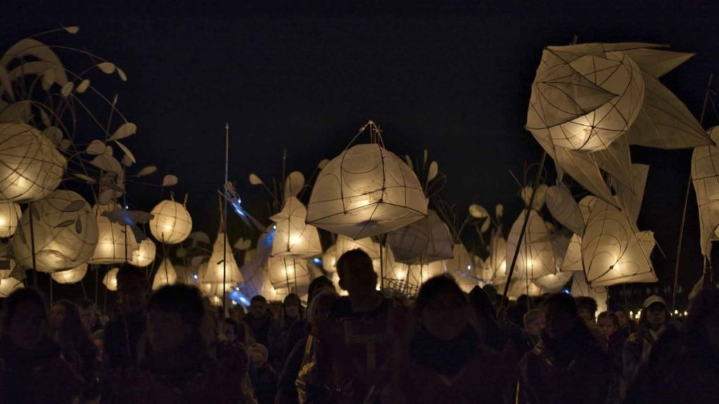 Des habitants défilent dans la nuit avec de grandes lanternes lumineuses lors de la parade des lanternes.